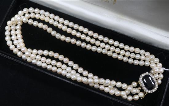 A three strand cultured pearl choker necklace, with oval sapphire and diamond set clasp, 38cm.